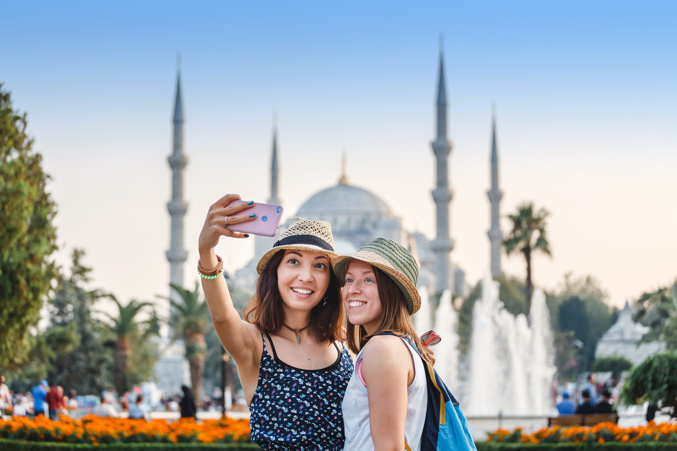 Eskapas Turkey tours Two smiling girlfriends with smart phone doing selfie in front of the Blue Mosque in Istanbul. Travel and vacation in Turkey concept