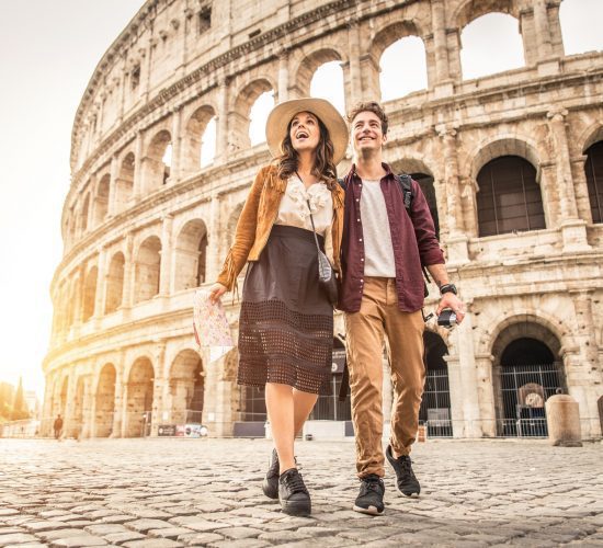 Young couple at the Colosseum, Rome - Happy tourists visiting italian famous landmarks