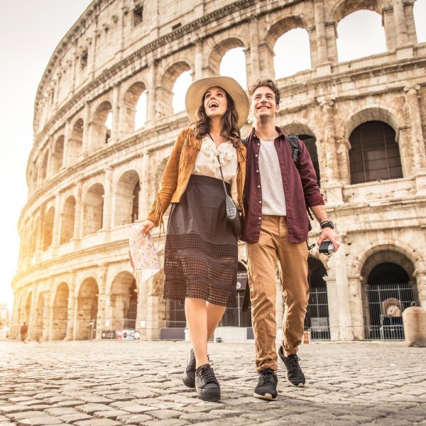Young couple at the Colosseum, Rome - Happy tourists visiting italian famous landmarks